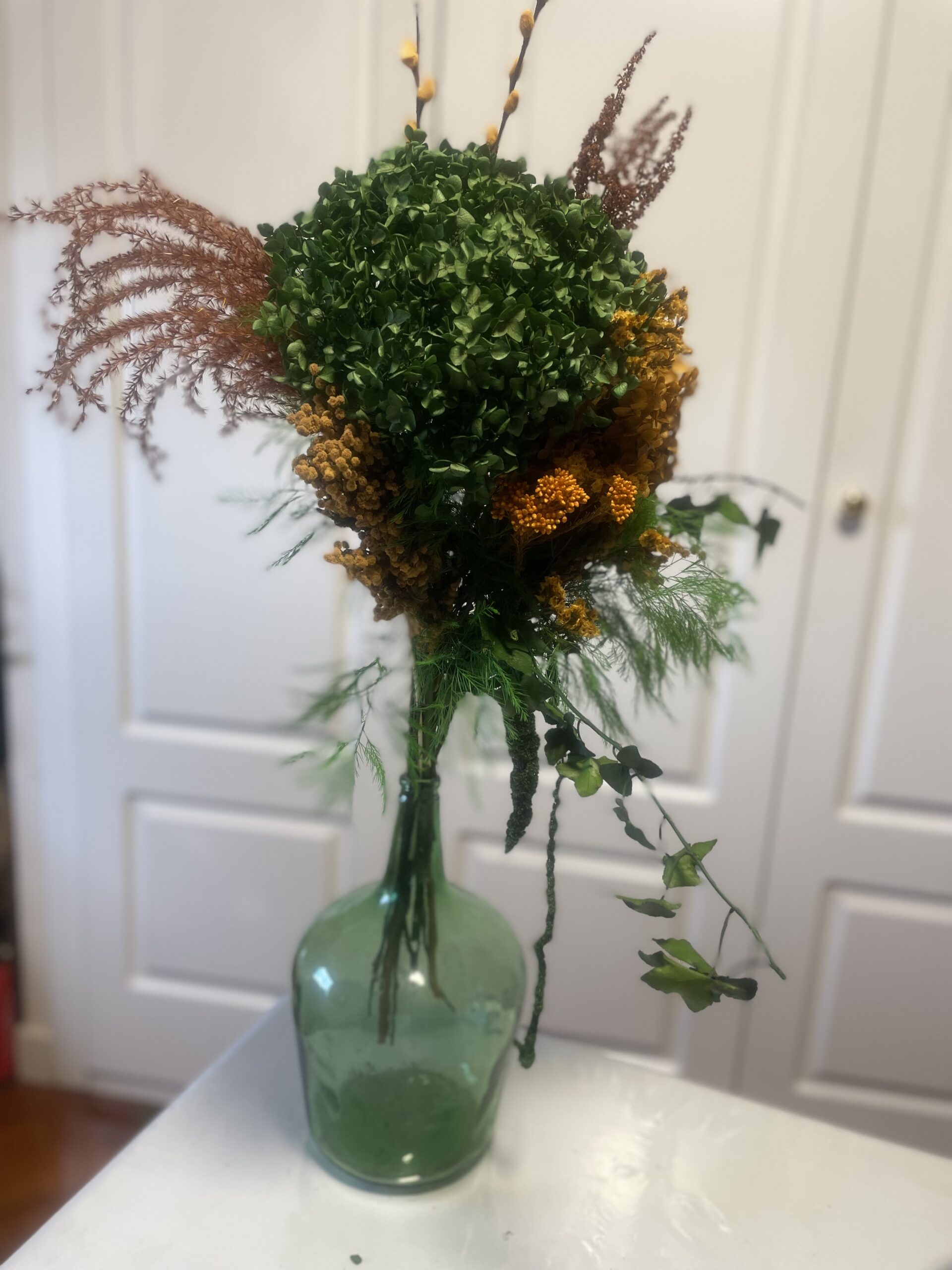 Damajuana con arreglo floral en tonos verdes y naranjas: imagen 2